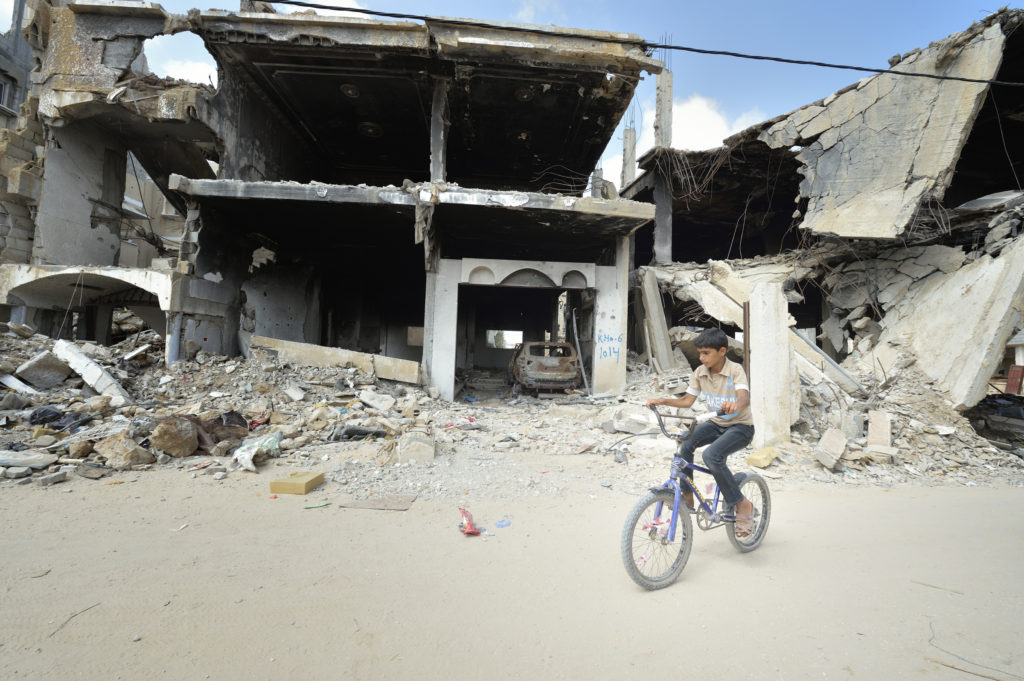 A boy rides his bike amid the ruins of Khan Younis, Gaza Strip, June 9. Houses in the area were destroyed during the 2014 war between Israel and the Hamas government of Gaza. (CNS photo/Paul Jeffrey) 