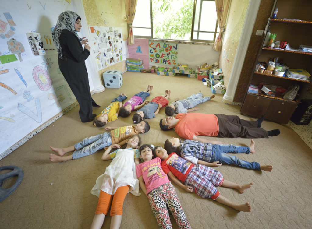 A woman leads a relaxation activity for children in Beit Hanoun, Gaza Strip, June 7. The program, designed to help children deal better with trauma and stress, is supported by Caritas Internationalis. (CNS photo/Paul Jeffrey) 