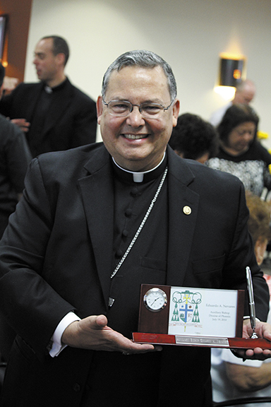 Bishop Eduardo A. Nevares, auxiliary bishop of the Diocese of Phoenix, displays an early five-year anniversary gift that bears his coat of arms. Each symbol honors his priestly ministry. His episcopal motto is "Serve the Lord with gladness." (Ambria Hammel/CATHOLIC SUN)