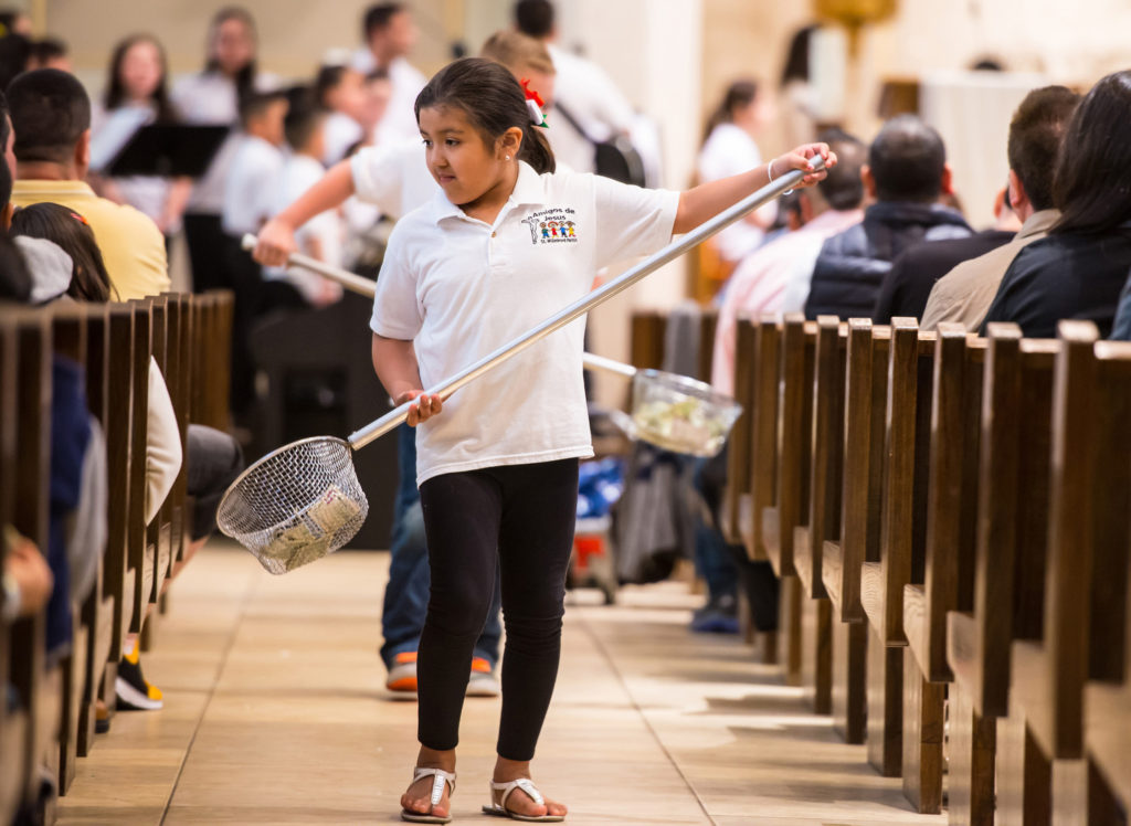 Hispanic Youth Group member Yelixa Hernandez helps collect donations during Mass at St. Willebrord Church in Green Bay, Wis., April 26. Hispanics are "not a problem to be solved" but are a blessing for the church, says a professor in analyzing a recent Boston College study. (CNS photo/Sam Lucero, The Compass) 