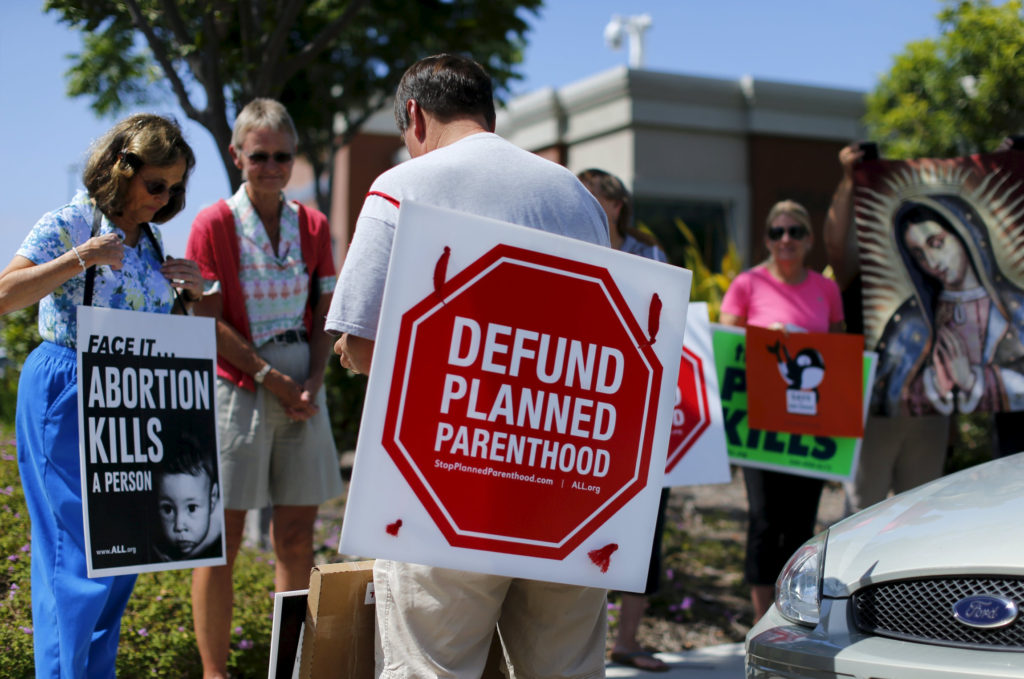 Protesters carry signs and an image of Our Lady of Guadalupe outside a Planned Parenthood clinic in Vista, Calif., Aug. 3. Boston Cardinal Sean P. O'Malley, head of the U.S. bishops' pro-life committee, urged U.S. senators to take the federal money that goes to the Planned Parenthood Federation of America and instead fund women's health care providers that do not promote abortion. (CNS photo/Mike Blake, Reuters) See OMALLEY-FUNDING Aug. 4, 2015.