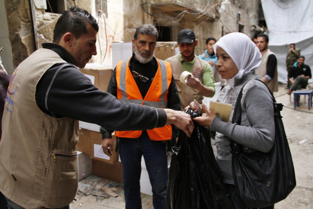 Staff members from the U.N. Relief and Works Agency for Palestine Refugees distribute aid in early March to residents of the al-Yarmouk Palestinian refugee camp near Damascus, Syria. To promote a reflection on the need for a "conversion of mind and heart" open to the needs of others, Pope Francis has chosen "Overcome indifference and win peace" as the theme for the church's celebration of the World Day of Peace 2016. (CNS photo/EPA)