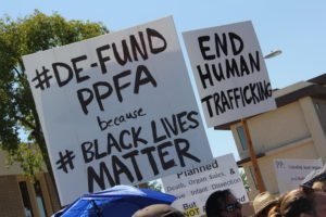 A protester carries a sign that references #BlackLivesMatter, a social media campaign meant to bring awareness to violence against African Americans, to highlight Planned Parenthood founder Margaret Sanger's racist leanings and the abortion provider's concentrated efforts in minority communities. (Justin Bell/CATHOLIC SUN)