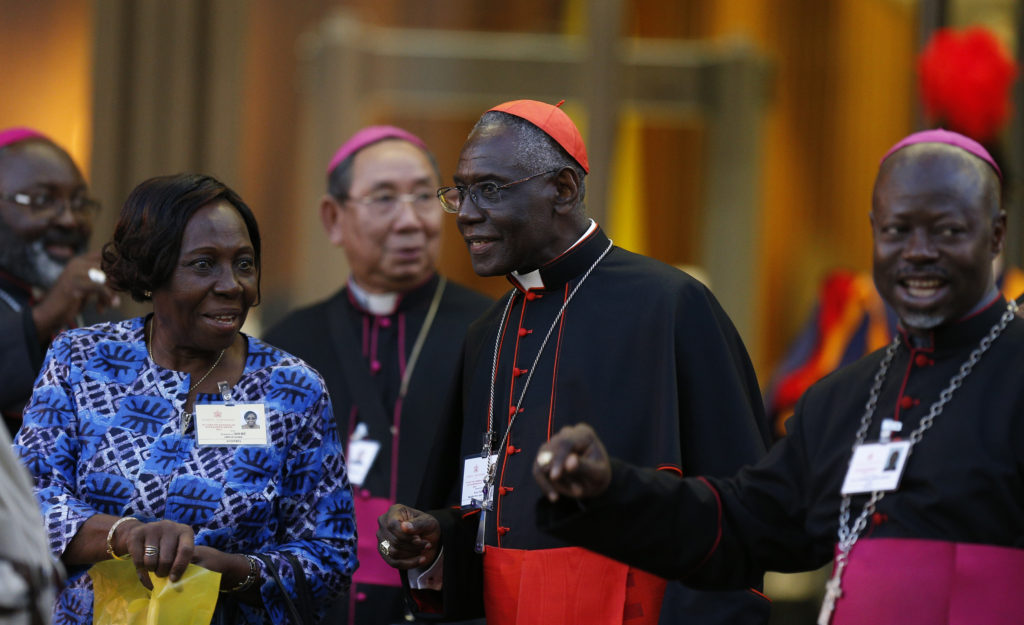 Cardinal Robert Sarah, president of the Pontifical Council Cor Unum, center, Jeannette Toure, an auditor from Ivory Coast, and bishops leave the concluding session of the extraordinary Synod of Bishops on the family at the Vatican Oct. 18. (CNS photo/Paul Haring) See SYNOD-MESSAGES and SYNOD-CONCLUSION Oct. 18, 2014.