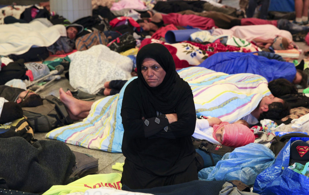 A woman sits among sleeping migrants near the Keleti railway station in Budapest, Hungary, Sept. 3. More than 2,000 migrants, many of them refugees from conflicts in the Middle East and Africa, camped in front of the Keleti Railway Terminus, closed to them by authorities who said European Union rules bar travel by those without valid documents. (CNS photo/Bernadett Szabo, Reuters) 