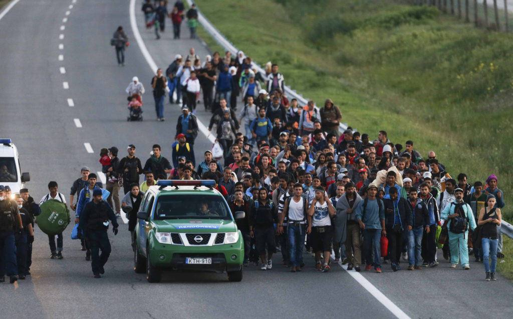 Hungarian police escort a group of migrants walking against the traffic on a highway Sept. 7 leading to Budapest as they left a transit camp in the village of Roszke. (CNS photo/Marko Djurica, Reuters) 