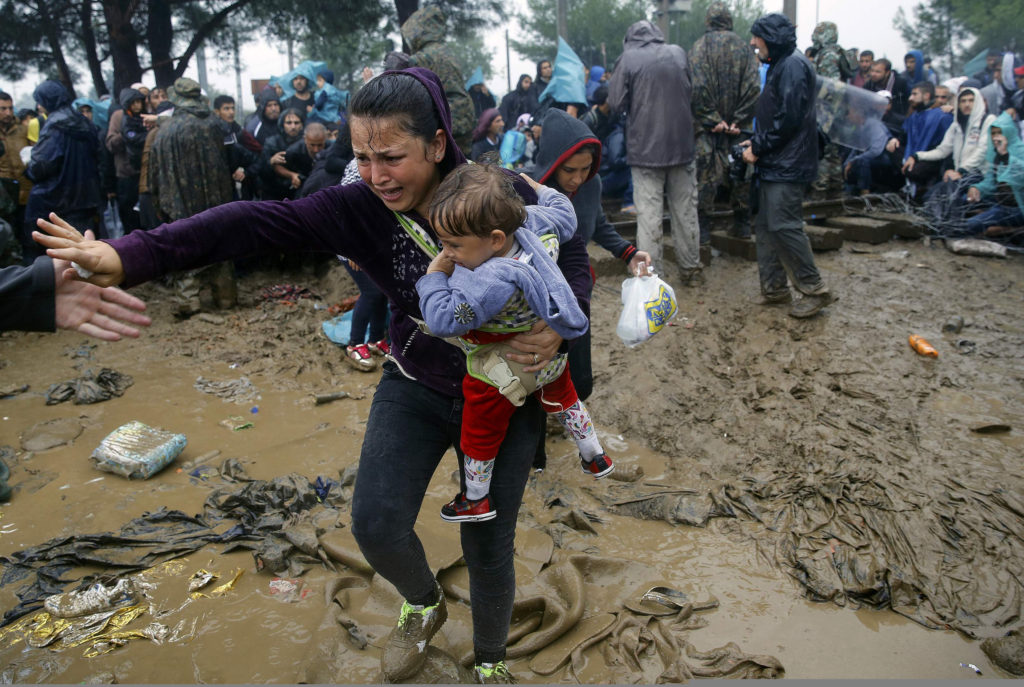 A Syrian refugee woman cries as she carries her baby through the mud to cross the border from Greece into Macedonia near the Greek village of Idomeni Sept. 10. Most of the people flooding into Europe are refugees fleeing violence and persecution in their home countries who have a legal right to seek asylum, the United Nations said Sept. 9. (CNS photo/Yannis Behrakis, Reuters) 