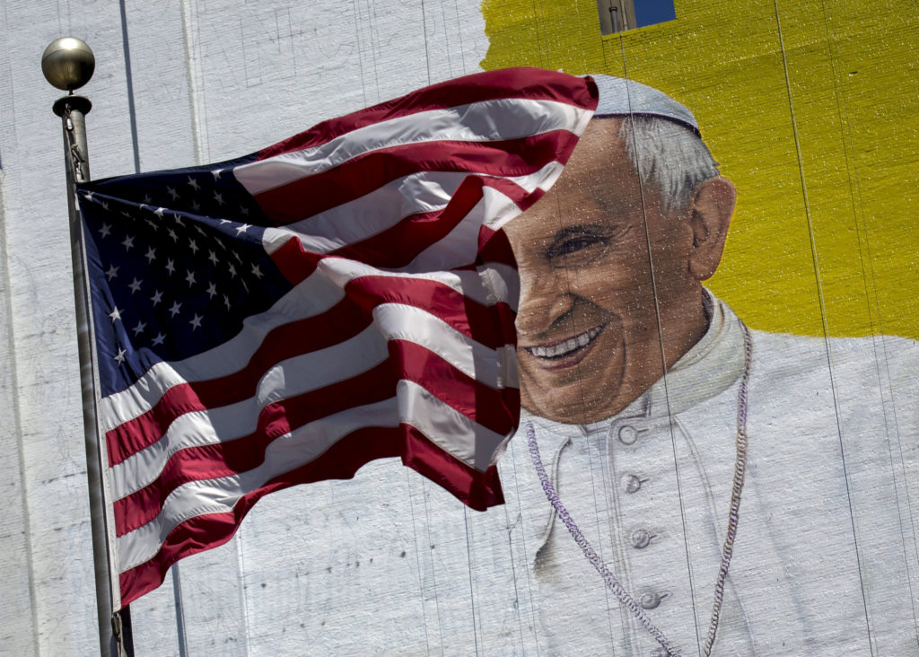The U.S. flag flies in front of a mural of Pope Francis in New York City, August 28. Pope Francis' 10th foreign trip will be the longest of his pontificate and, with stops in Cuba, three U.S. cities and the United Nations, it also will be a "very complex trip," the papal spokesman said. (CNS photo/Brendan McDermid, Reuters) 