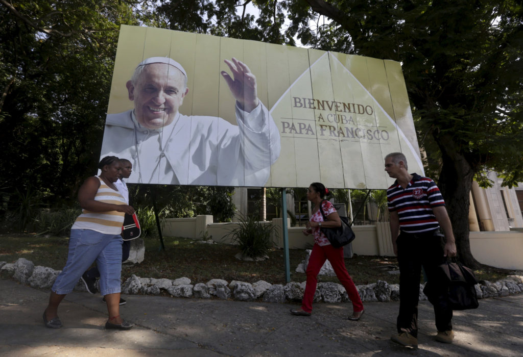 Cubans walk under a Pope Francis billboard in Havana, Sept. 14, 2015. Pope Francis' 10th foreign trip will be the longest of his pontificate and, with stops in Cuba, three U.S. cities and the United Nations, it also will be a "very complex trip," the papal spokesman said. (CNS photo/Enrique de la Osa, Reuters) 
