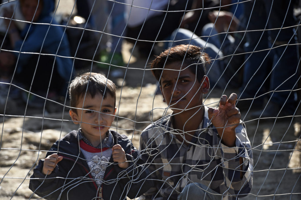 Migrant children look through a fence as they wait permission to cross the border between Greece and Macedonia Sept. 15. "Do not abandon victims" of conflicts in Syria and Iraq, Pope Francis said. (CNS photo/Georgi Licovski, EPA) 