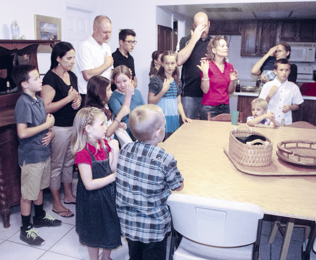 Members of the Fowler, Phelan and Hanning families pray before sharing a meal Sept. 8 in Mesa. All three families will travel with their children to Philadelphia for the World Meeting of Families. (Joyce Coronel/ CATHOLIC SUN)