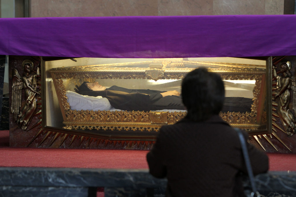 In this 2014 file photo, A woman prays before the body of St. Frances Xavier Cabrini, which rests in a glass casket under the altar in the saint's shrine chapel in the Washington Heights section of New York City. The chapel adjoins Mother Cabrini High School, an all-girls college preparatory school the saint founded in 1899. (CNS photo/Gregory A. Shemitz)
