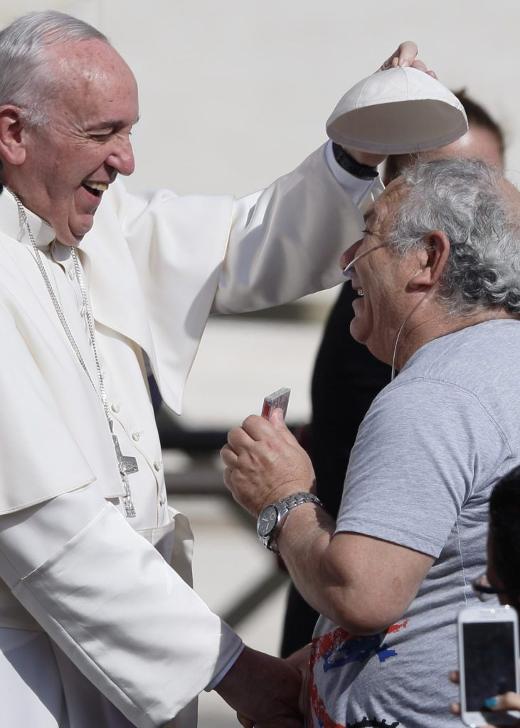 Pope Francis places his zucchetto on Salvatore Sessa's head during his general audience in St. Peter's Square at the Vatican Oct. 7. The pope said that when families mirror God's love for all, they teach the church how it should relate to all people. (CNS photo/Paul Haring) 