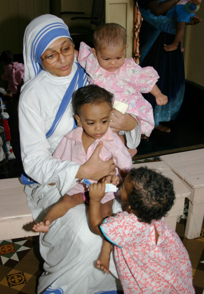 A member of the Missionaries of Charity holds orphan children in 2007 at a center in Kolkata, India. The Missionaries of Charity will close their adoption centers in India, citing new regulations that would allow nontraditional families to adopt children, reported ucanews.com. (CNS photo/Anto Akkara)