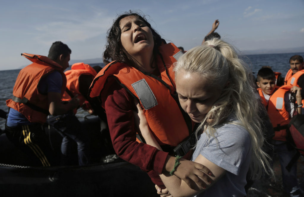 A Syrian girl reacts as she helped by a volunteer upon her Oct. 9 arrival from Turkey to the Greek island of Lesbos. Greece is bracing for thousands more Syrian and other migrants to land on Lesbos and other key island crossings from Turkey, as those fleeing conflict remain undeterred by the worsening weather and colder autumn temperatures. (CNS photo/Yannis Kolesidis, EPA) 