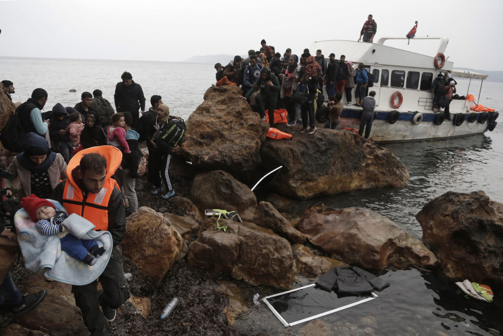 Migrants from Syria arrive on the Greek island of Lesbos Oct. 11 on an overcrowded fishing boat after crossing the Aegean sea from Turkey. Greece is bracing for thousands more Syrian and other migrants to land on Lesbos and other key island crossings from Turkey, as those fleeing conflict remain undeterred by the worsening weather and colder autumn temperatures. (CNS photo/Yannis Kolesidis, EPA)