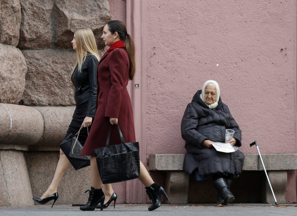 An elderly woman asks for money as women pass her by in Kiev, Ukraine, Oct.23. While they did not grab headlines, the topics of elderly and people with disabilities, openness to life and the plight of migrants and refugees were also on the agenda of the Synod of Bishops on the family. (CNS photo/Sergey Dolzhenko, EPA)
