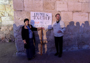 Peta Jones Pellach, an Orthodox Jewish woman who works for the Elijah Interfaith Institute, and Anglican Father Nicholas Taylor of Scotland, hold a sign at an interfaith prayer service for peace in the Old City of Jerusalem Oct. 29. (CNS photo/Debbie Hill) 