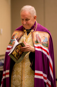 Bishop Gerald N. Dino of the Byzantine Eparchy of Phoenix flips through the program before the event. This was the first year that Bishop Dino participated in the Arizona Rosary Celebration. (Billy Hardiman/CATHOLIC SUN)