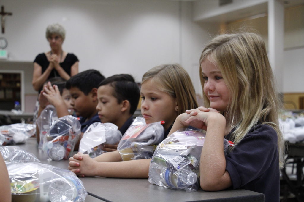 Third-graders at Ss. Simon and Jude pray over the "Packages of Hope" they assembled Sept. 25. Each student planned to give it to a person in need they encountered on the street. (Ambria Hammel/CATHOLIC SUN)