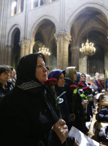 Women hold roses as Cardinal Andre Vingt-Trois of Paris celebrates a Mass in Notre Dame Cathedral in Paris Nov. 15 to pray for those killed in terrorist attacks. Coordinated attacks the evening of Nov. 13 claimed the lives of 129 people. The Islamic State claimed responsibility. (CNS photo/Paul Haring) 
