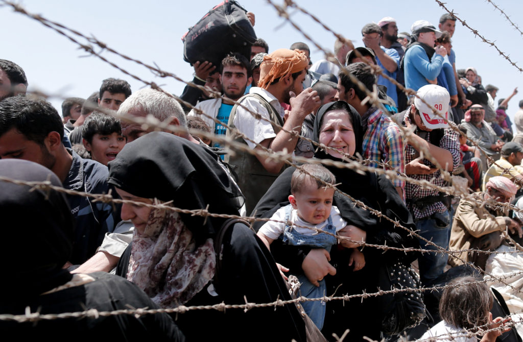 Syrian refugees wait on the Syrian side of the border near Sanliurfa, Turkey, June 10. Bishop Eusebio Elizondo, chairman of the U.S. Conference of Catholic Bishops' Committee on Migration, says the United States should welcome Syrian refugees and work for peace. (CNS photo/Sedat/Suna, EPA)