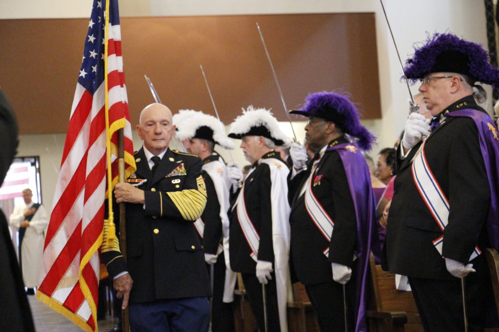 A veteran processes in with the American flag during the Nov. 8 Red, White and Blue Mass at St. Thomas Aquinas Parish in Avondale. A flag from each branch of the military plus the U.S. and papal flags added patriotic imagery to the liturgy. (Ambria Hammel/CATHOLIC SUN)