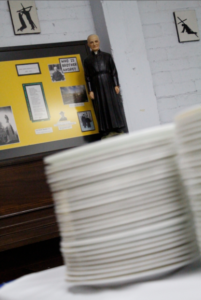 A statue of St. André Bessette overlooks a stack of plates that André House staff, volunteers and other guests used during an anniversary dinner Oct. 30. (Ambria Hammel/CATHOLIC SUN)