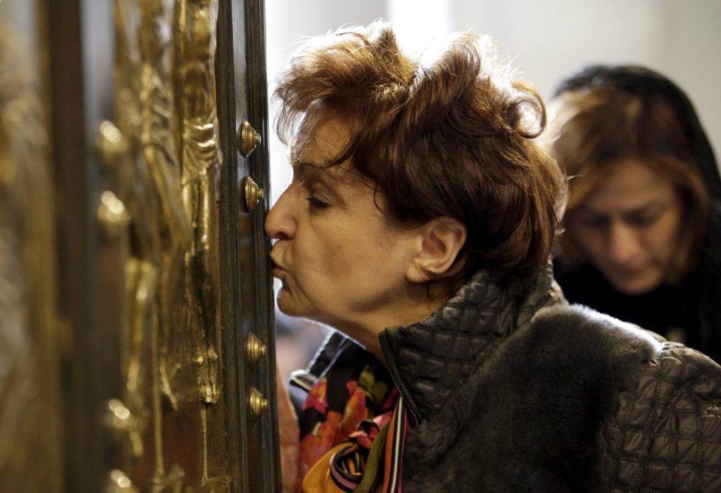 A woman kisses the Holy Door in St. Peter's Basilica after Pope Francis opened it to mark the inauguration of the Jubilee Year of Mercy at the Vatican Dec. 8. (CNS photo/Max Rossi, Reuters)