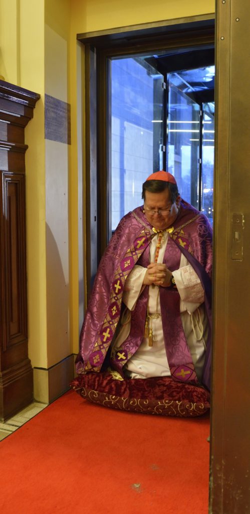 Cardinal Gerald Lacroix of Quebec kneels in prayer in the Holy Door frame prior to a Dec. 12 Mass for the opening of the door in Notre-Dame Cathedral. (CNS photo/Daniel Abel) 