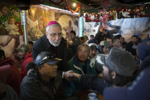 Bishop Gerald F. Kicanas of Tucson greets men at the "comedor," the kitchen and dining hall of the Aid Center for Deported Migrants in Nogales, Mexico, Dec. 20. Bishop Kicanas and Nogales Bishop Jose Leopoldo Gonzalez Gonzalez visited with migrants after taking part in a binational "posada," a commemoration of Mary and Joseph’s search for a place to give birth to Jesus. (CNS photo/Nancy Wiechec) 
