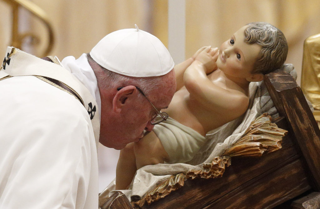Pope Francis kisses a figurine of the baby Jesus as he arrives to celebrate Christmas Eve Mass in St. Peter's Basilica at the Vatican Dec. 24. (CNS photo/Paul Haring) 