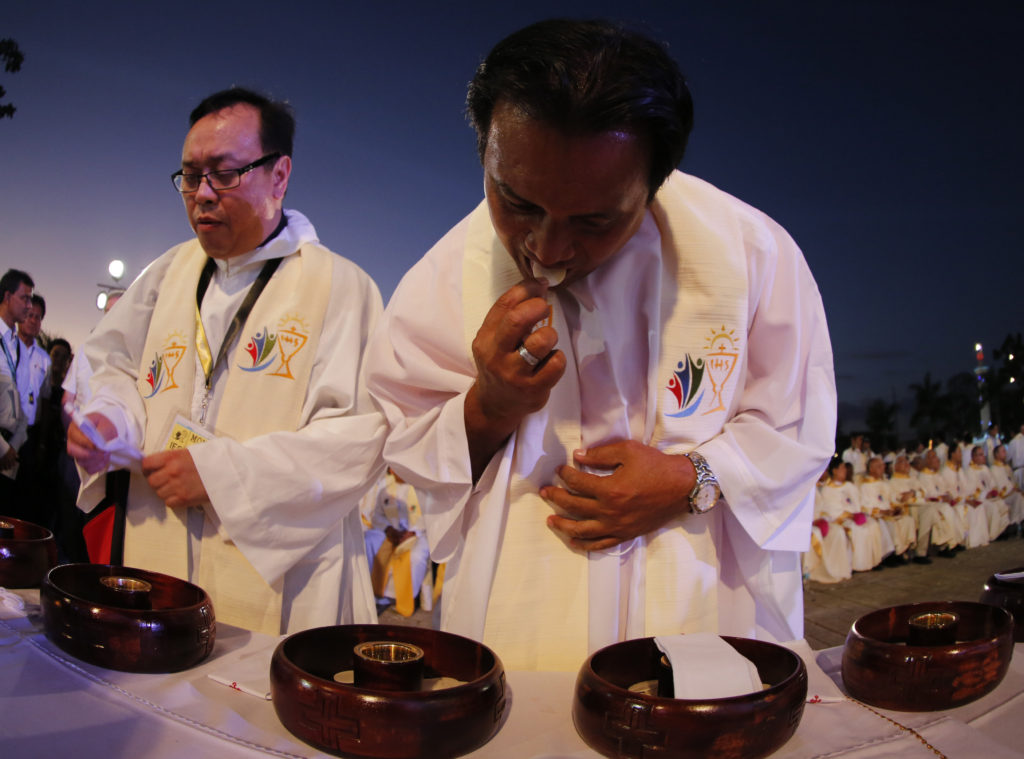 A priest consumes remaining hosts from the Eucharist during a Mass at the 51st International Eucharistic Congress in Cebu, Philippines, Jan. 24. (Francis R. Malasig/CNS via EPA)