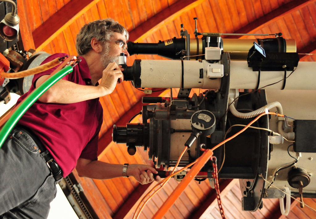 Jesuit Brother Guy Consolmagno, directory of the Vatican Observatory, looks through one of the telescopes at Castel Gandolfo. (Photo courtesy of Katie Bannan Steinke, Vatican Observatory Foundation)