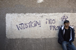A man leans against a wall near the international border in Nogales, Mexico, Dec. 20. The graffiti reads, "Justice! No Borders!" (CNS photo/Nancy Wiechec) 