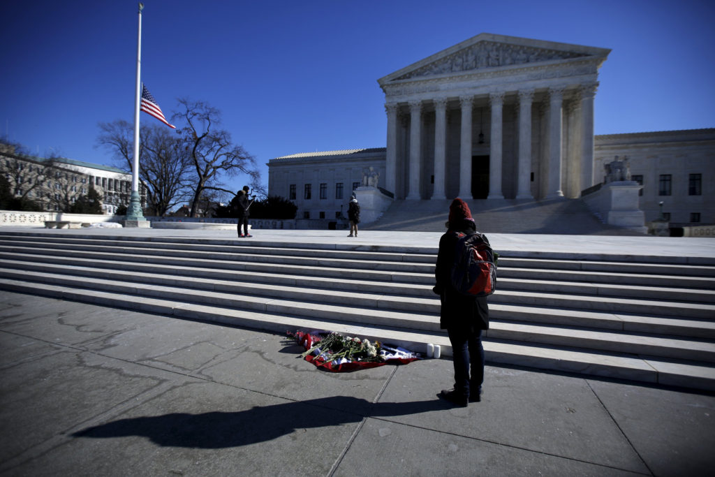 A woman stands in front of flowers outside the Supreme Court building in Washington Feb. 14, the day after the death of U.S. Supreme Court Justice Antonin Scalia. (CNS photo/Carlos Barria, Reuters) 