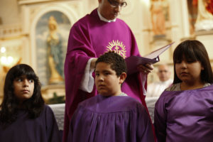 Jesuit Father Ron Gonzales blesses young catechumens during Mass Feb. 14 at Sacred Heart Parish in the Segundo Barrio of El Paso, Texas. During Pope Francis' visit to Mexico, members of Sacred Heart prayed twice each day for his intentions of mercy and peace and for his safety. The church is located a few blocks from the border with Mexico. (CNS photo/Nancy Wiechec)