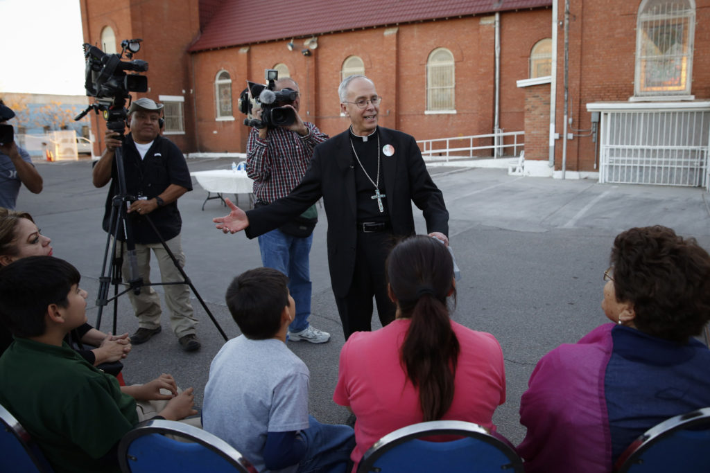 Bishop Mark J. Seitz of El Paso, Texas, talks with residents of the Segundo Barrio outside St. Ignatius Church in El Paso Feb. 15. He handed out tickets to the diocese's "Two Nations, One Faith" event, which will coincide with Pope Francis' visit Feb. 17 to El Paso's sister city, Ciudad Juarez, Mexico. (CNS photo/Nancy Wiechec)