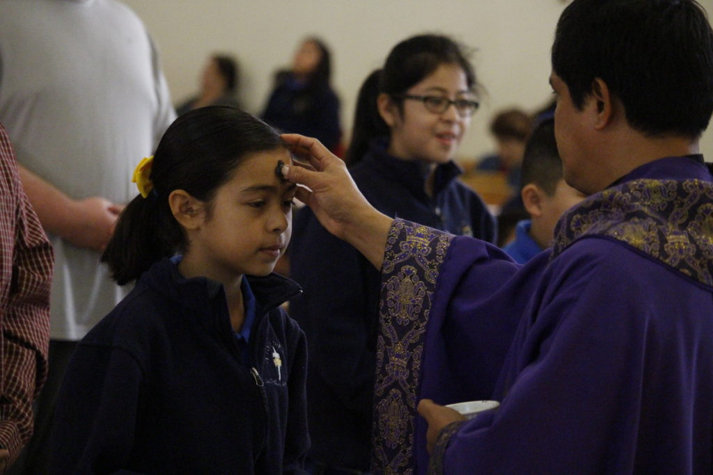 Fr. Joal Bernales marks a St. Louis the King student with ashes on her forehead Feb. 10. (Ambria Hammel/CATHOLIC SUN)