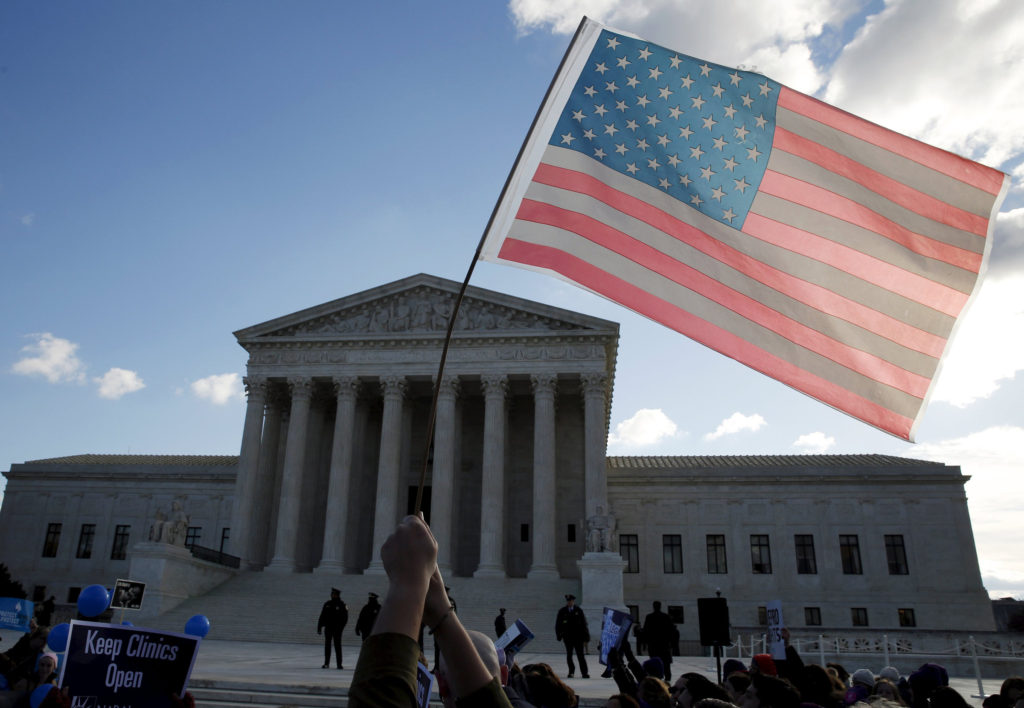 A person holds up the American flag in front of the U.S. Supreme Court in Washington March 2. (CNS photo/Kevin Lamarque, Reuters) 