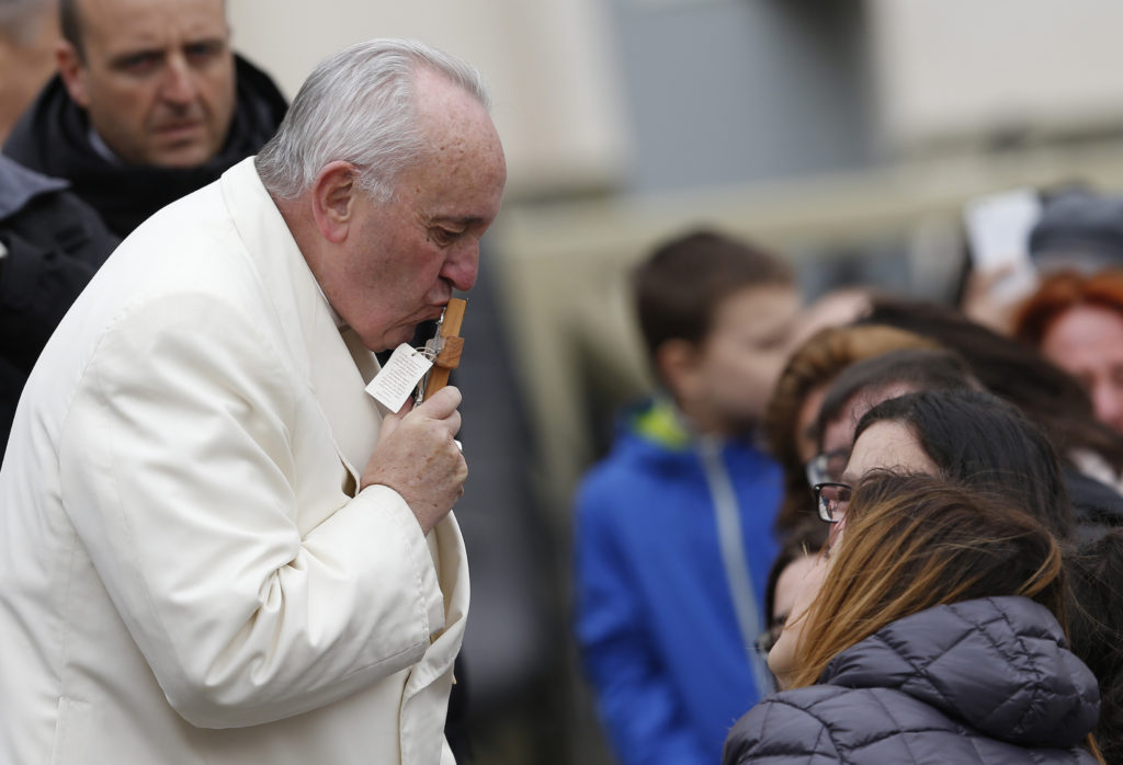 Pope Francis kisses a crucifix given by someone while meeting the disabled during his general audience in St. Peter's Square at the Vatican March 23. (CNS photo/Paul Haring) 