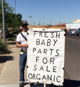 Steven Sivigliano holds a large sign that takes a jab at Planned Parenthood, which was exposed last year in a series of undercover videos in which personnel discussed the sale of aborted fetuses. (Joyce Coronel/CATHOLIC SUN)