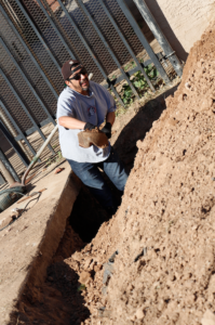 David Martinez shovels dirt from under the parish sidewalk at Blessed Sacrament in Tolleson Feb. 25 to expose a faulty plumbing line. (Ambria Hammel/CATHOLIC SUN)