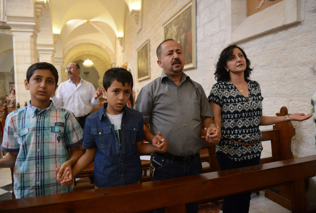 A family prays in 2014 in the Church of St. Catherine in Bethlehem, West Bank. Pope Francis' postsynodal apostolic exhortation on the family, "Amoris Laetitia" ("The Joy of Love"), was to be released April 8. The exhortation is the concluding document of the 2014 and 2015 synods of bishops on the family. (CNS photo/Debbie Hill)