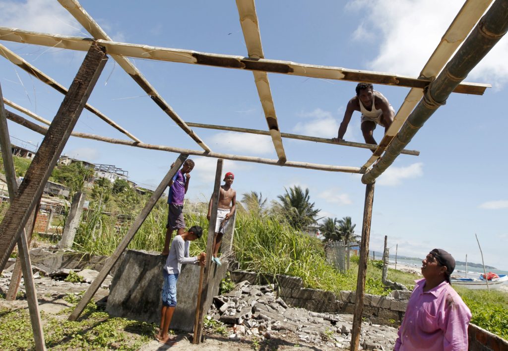 A man works on the roof as he rebuilds his house April 25 in Pedernales, Ecuador. Catholic agencies will begin building temporary shelters for thousands of families displaced by the April 16 magnitude-7.8 earthquake, the country's worst natural disaster in nearly seven decades. (CNS photo/Guillermo Granja, Reuters) 