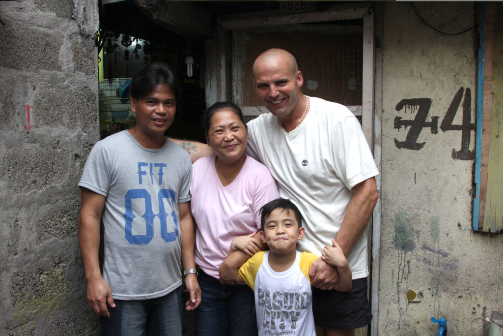Mark Crosbie poses for a photo with Mel and Merney Macaereg and one of their six children in Manila, Philippines, in this undated photo. Crosbie, an Irish Catholic street cleaner who was filmed for a job-swap TV documentary, has pledged to spend the rest of his life helping the struggling family he lived with in Manila. (CNS photo/courtesy RTE) 