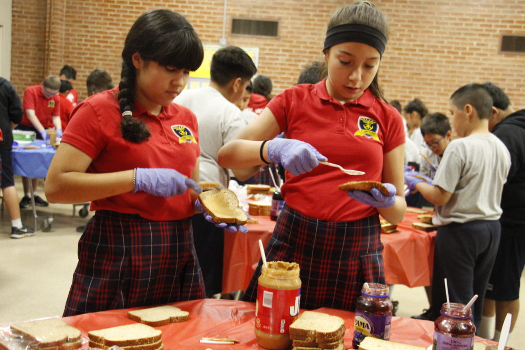 Junior high students make peanut butter and jelly sandwiches to distribute to André House guests April 13. (Ambria Hammel/CATHOLIC SUN)
