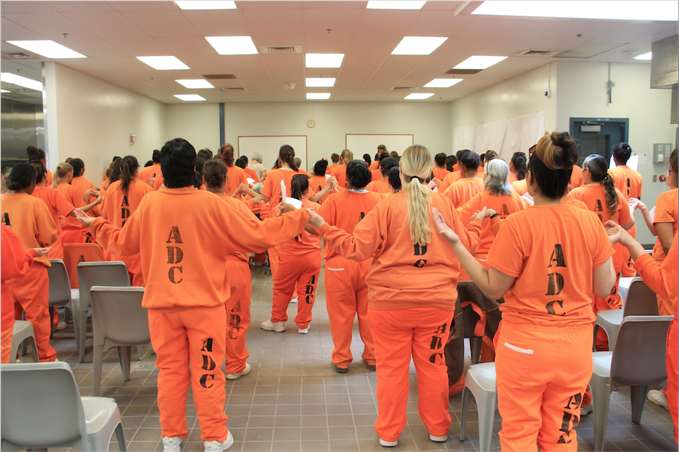 Female inmates pray the Our Father during an Easter Mass at Perryviille State Prison Complex March 27. Some women local Catholic volunteers have worked with have gone on to complete their sacraments while behind bars. Wives of inmates have gone on healing retreats thanks to efforts of the diocesan Prison Ministry. (Tony Gutierrez/CATHOLIC SUN)