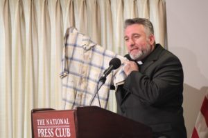 Fr. Douglas Bazi holds up the blood-stained shirt he was wearing when he was abducted and tortured for nine days by Islamic terrorists in 2006 during a press conference hosted by In Defense of Christians and the Knights of Columbus in Washington, D.C., on March 10, 2016. (Photo courtesy of Fr. Bazi)