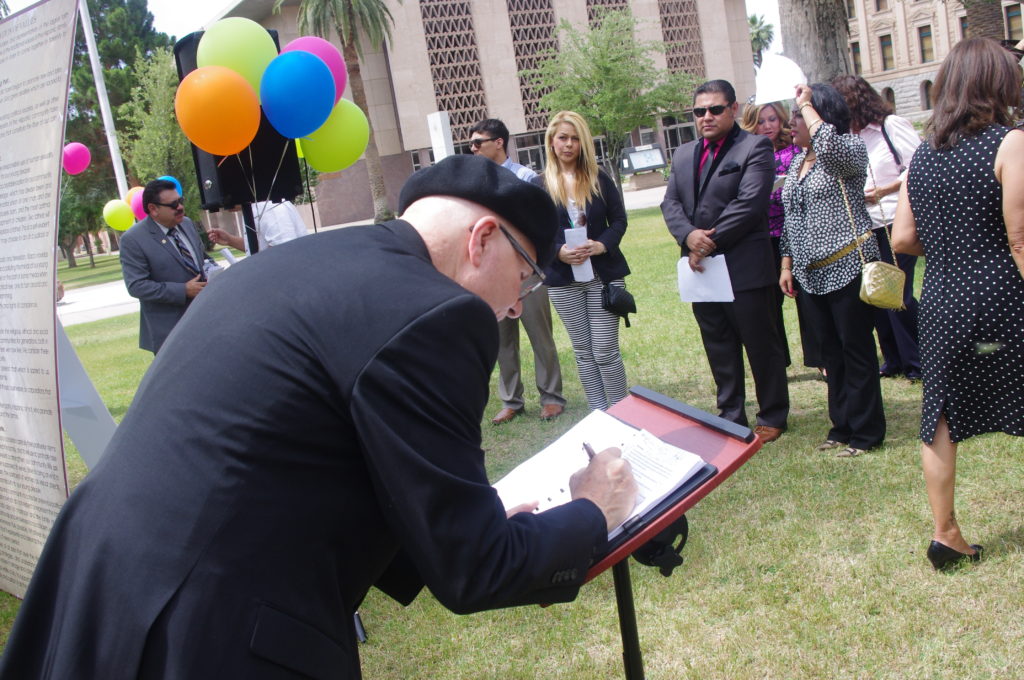 Fr. Charles Goraieb, pastor of St. Timothy Catholic Church, signs the Declaration of Values in front of the Capitol May 14. (Joyce Coronel/CATHOLIC SUN)